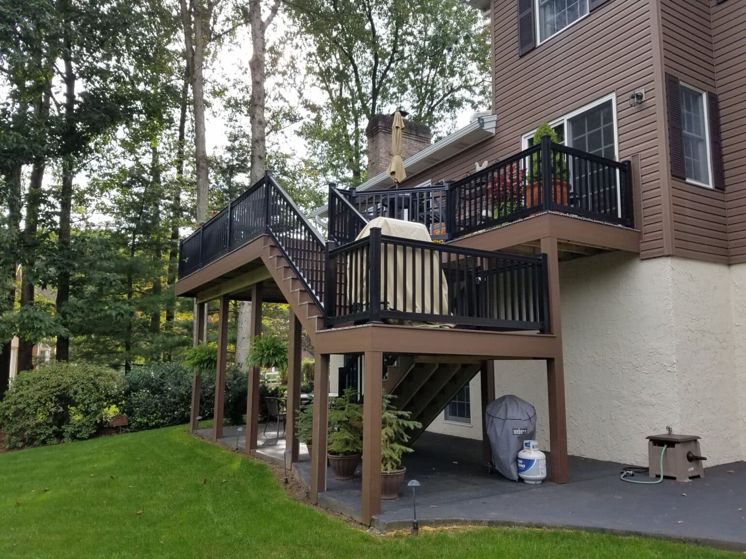 a vinyl deck with a black railing and a green lawn