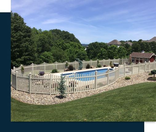 A backyard with a fenced swimming pool, surrounded by greenery and a small shed nearby on a sunny day.