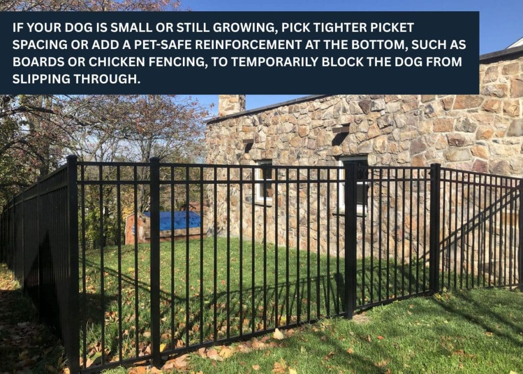 Black aluminum fence enclosing a backyard near a stone house.